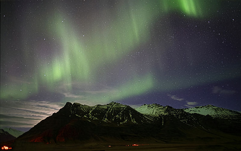 Vivid green Aurora Borealis over snow-capped Icelandic mountains at night
